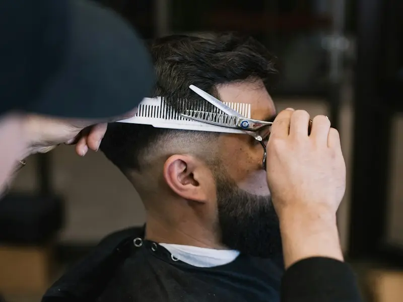 A barber cutting hair with scissors and a comb