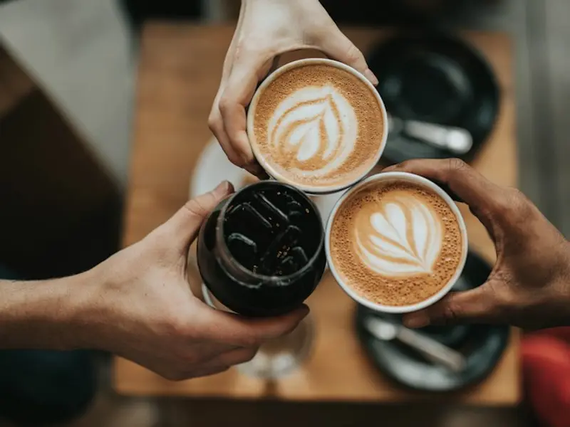 Friends holding cups of coffee together
