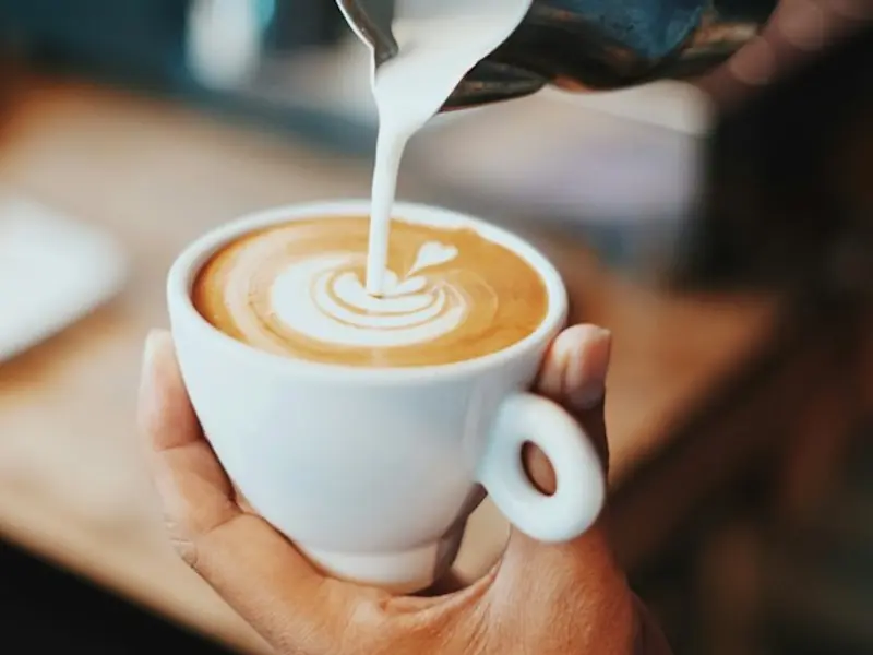 Milk being poured into a cup of coffee